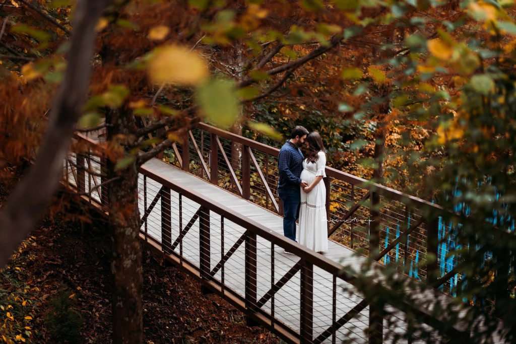 husband and wife embracing eachother on a industrial bridge during their Crystal Bridges maternity session