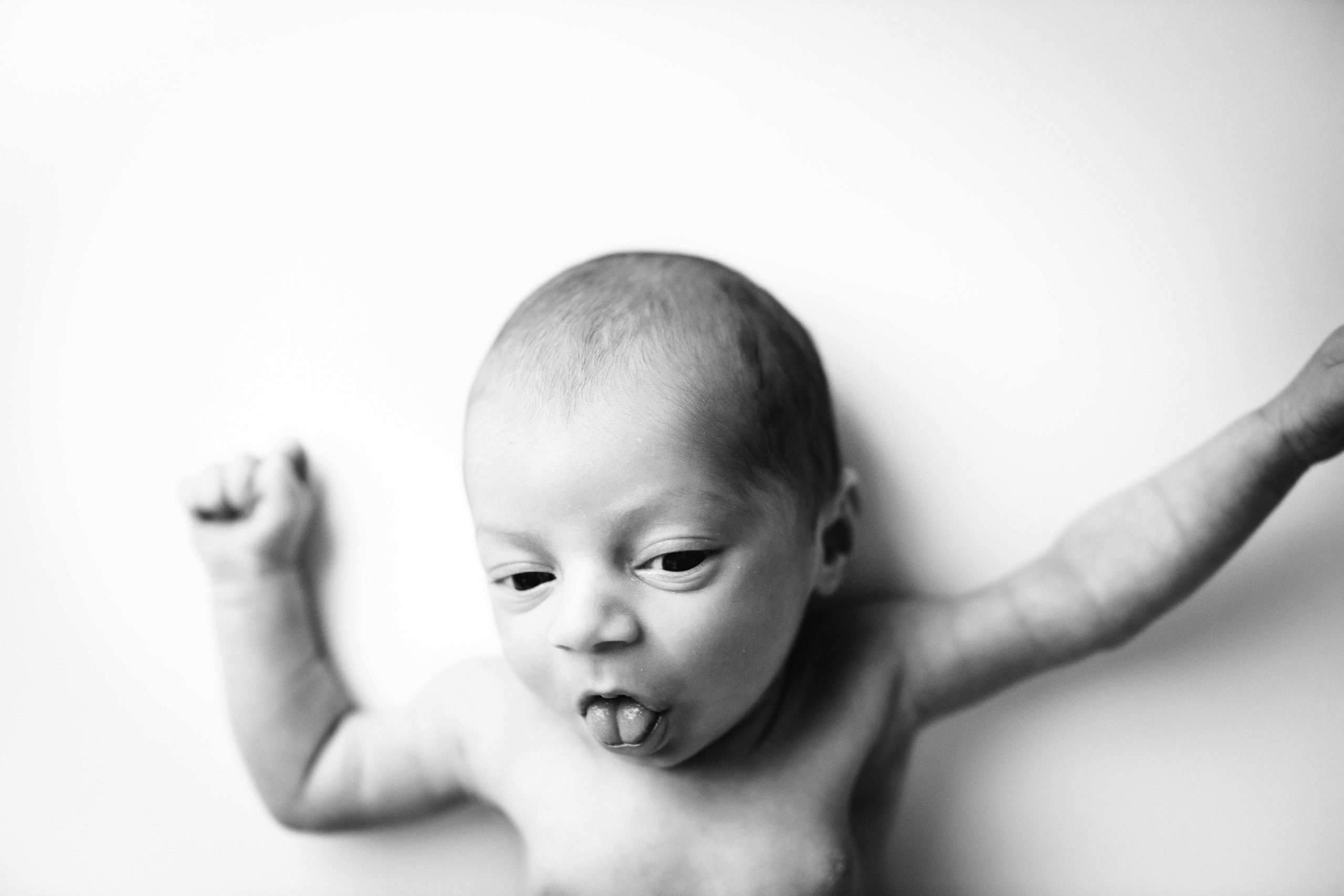 Baby on white backdrop sticking his tongue out