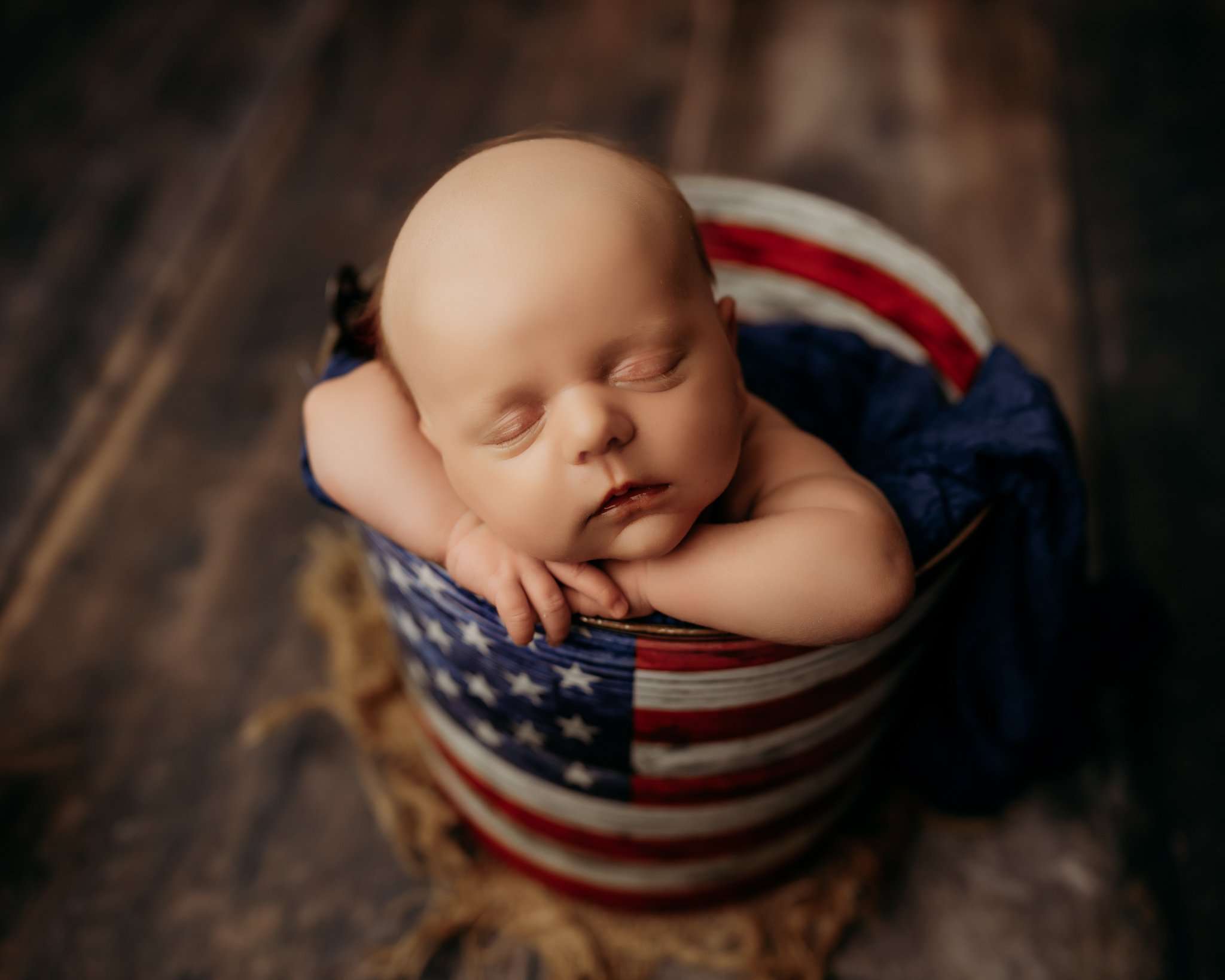 baby in bucket sleeping with head on its hands
