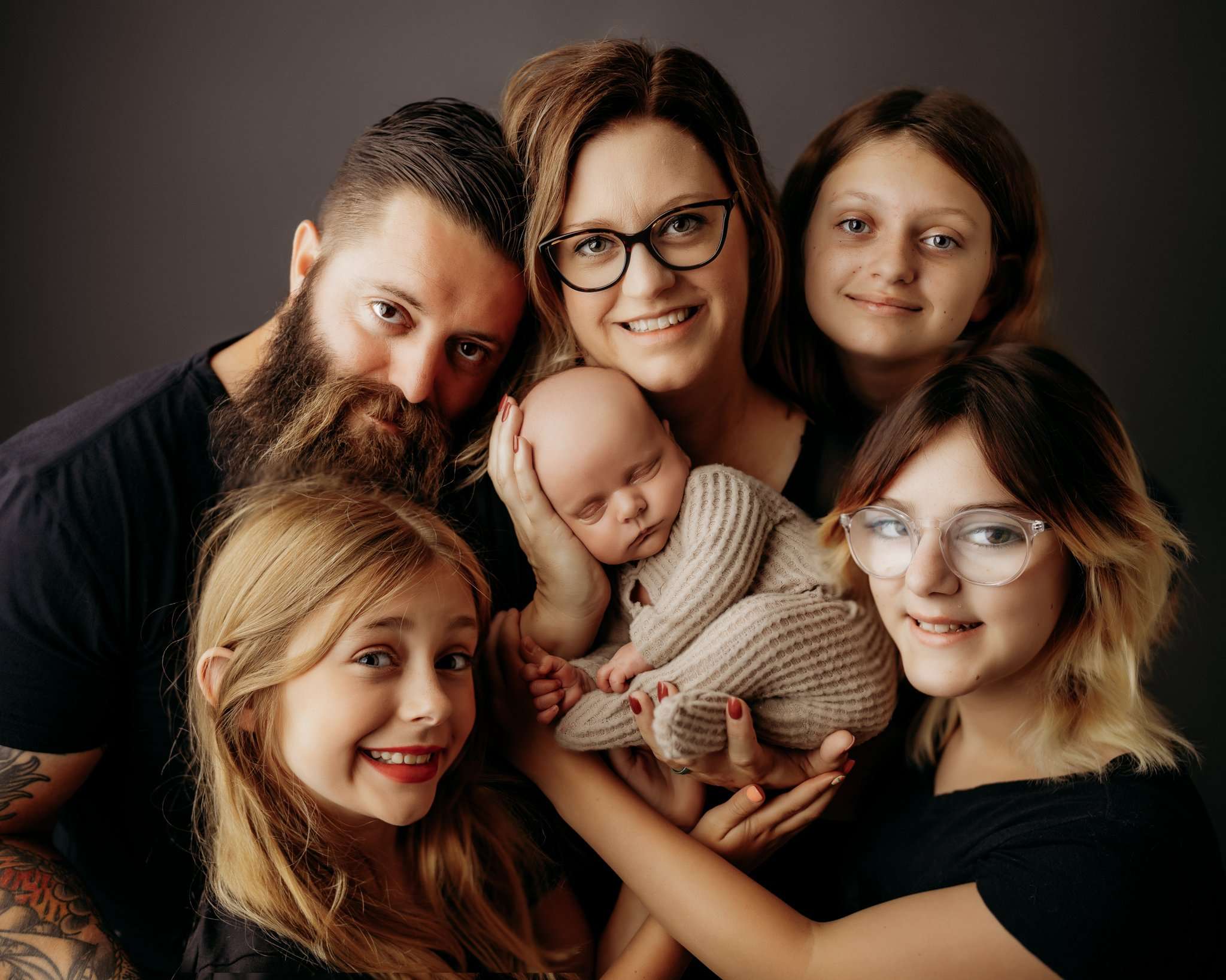 family image on dark gray backdrop surrounding the newborn in the family