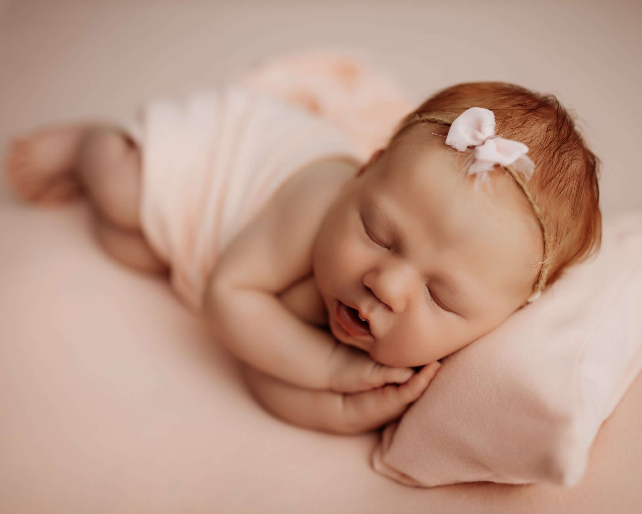 NWA newborn photography session on pink backdrop with baby in side laying pose with pillow under her head