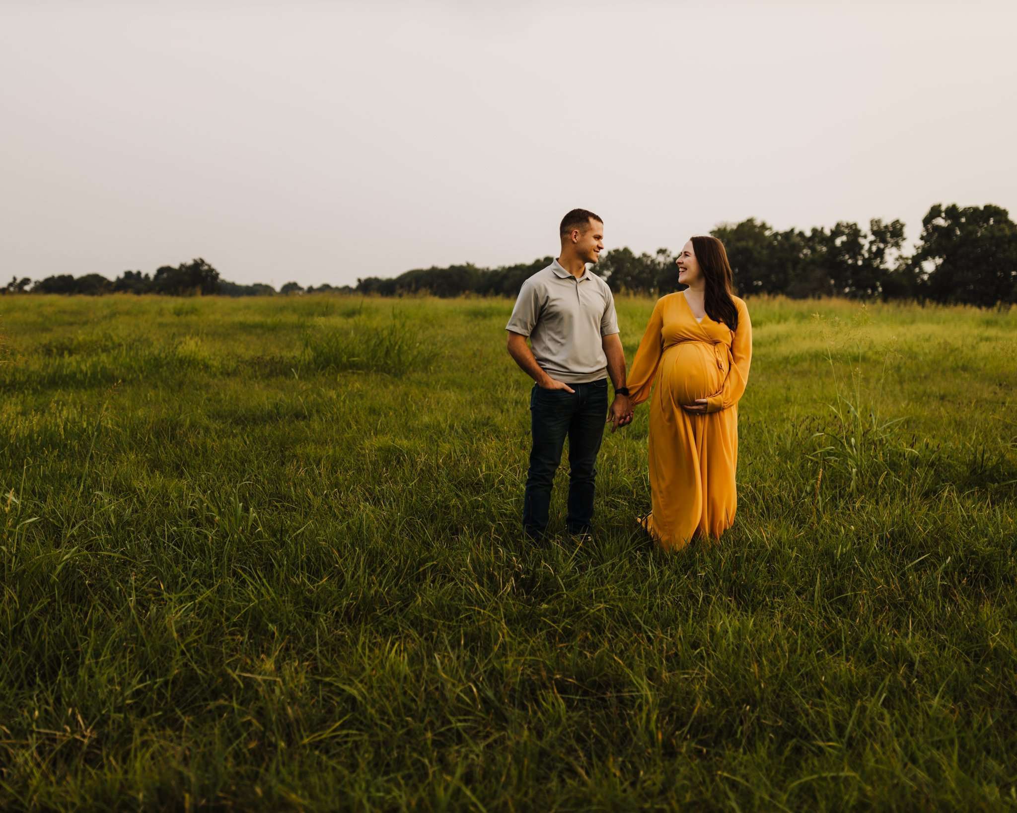 maternity images done in open field with mom wearing a yellow/orange dress