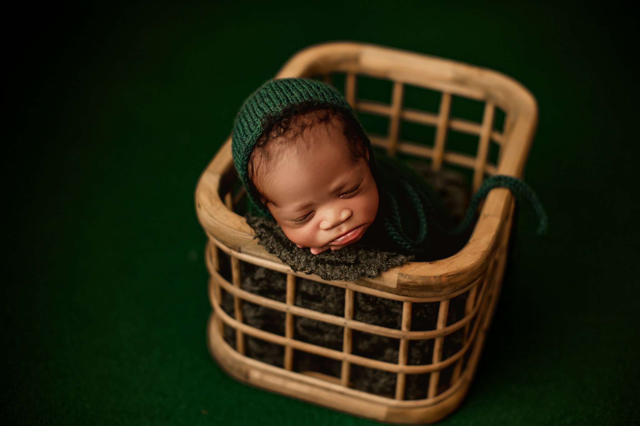 NWA best newborn photographer newborn in potato wrap in a crate on a dark green backdrop